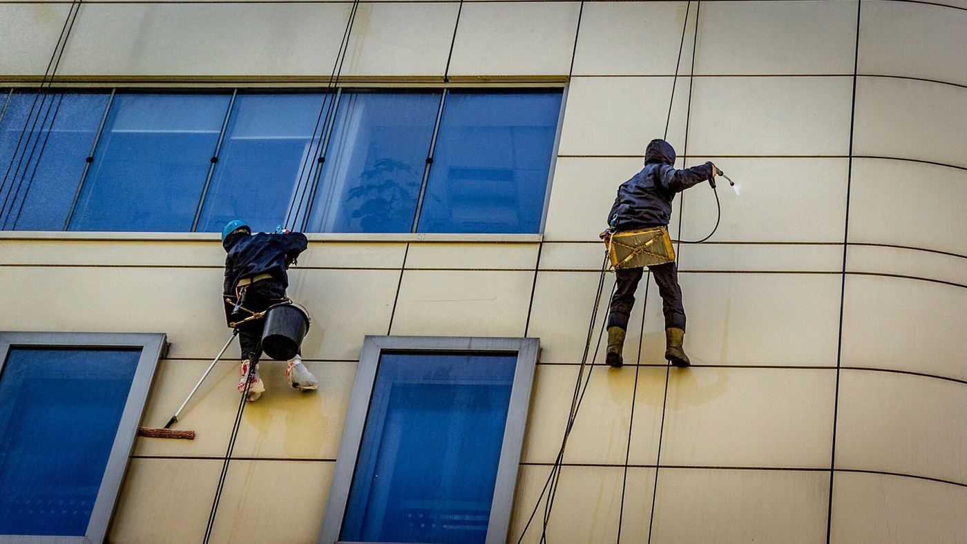 Two technicians cleaning a commercial facade